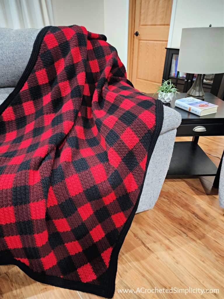 Crochet c2c plaid blanket draped over the side of a couch.