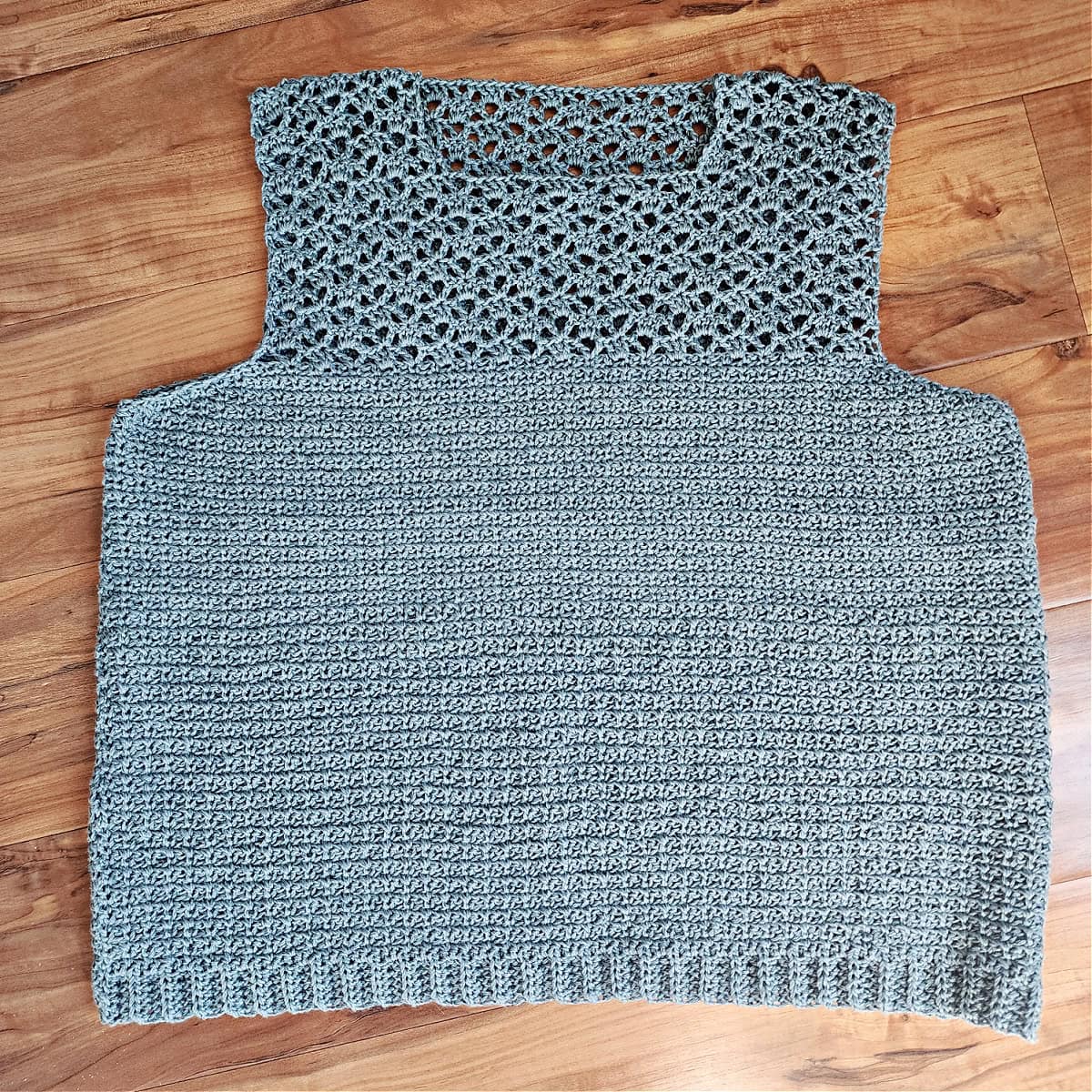The front and back panels of a lightweight crochet summer top seamed at the shoulders and sides.