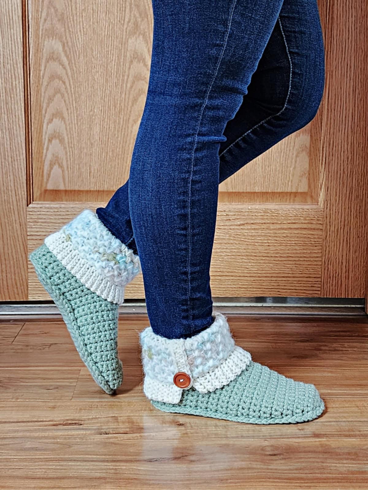 Pair of crochet slipper boots on model with blue jeans and one leg kicked back.