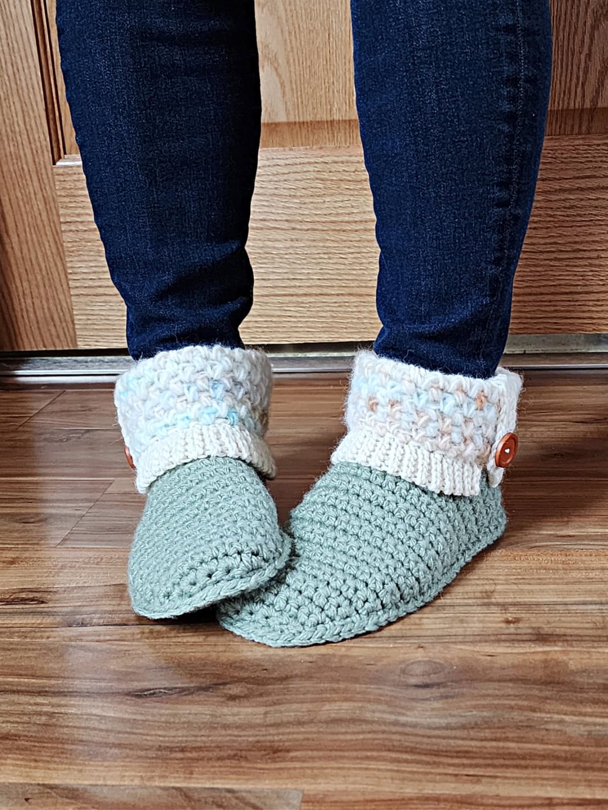 Green slipper boots with cream cuff on model with blue jeans.