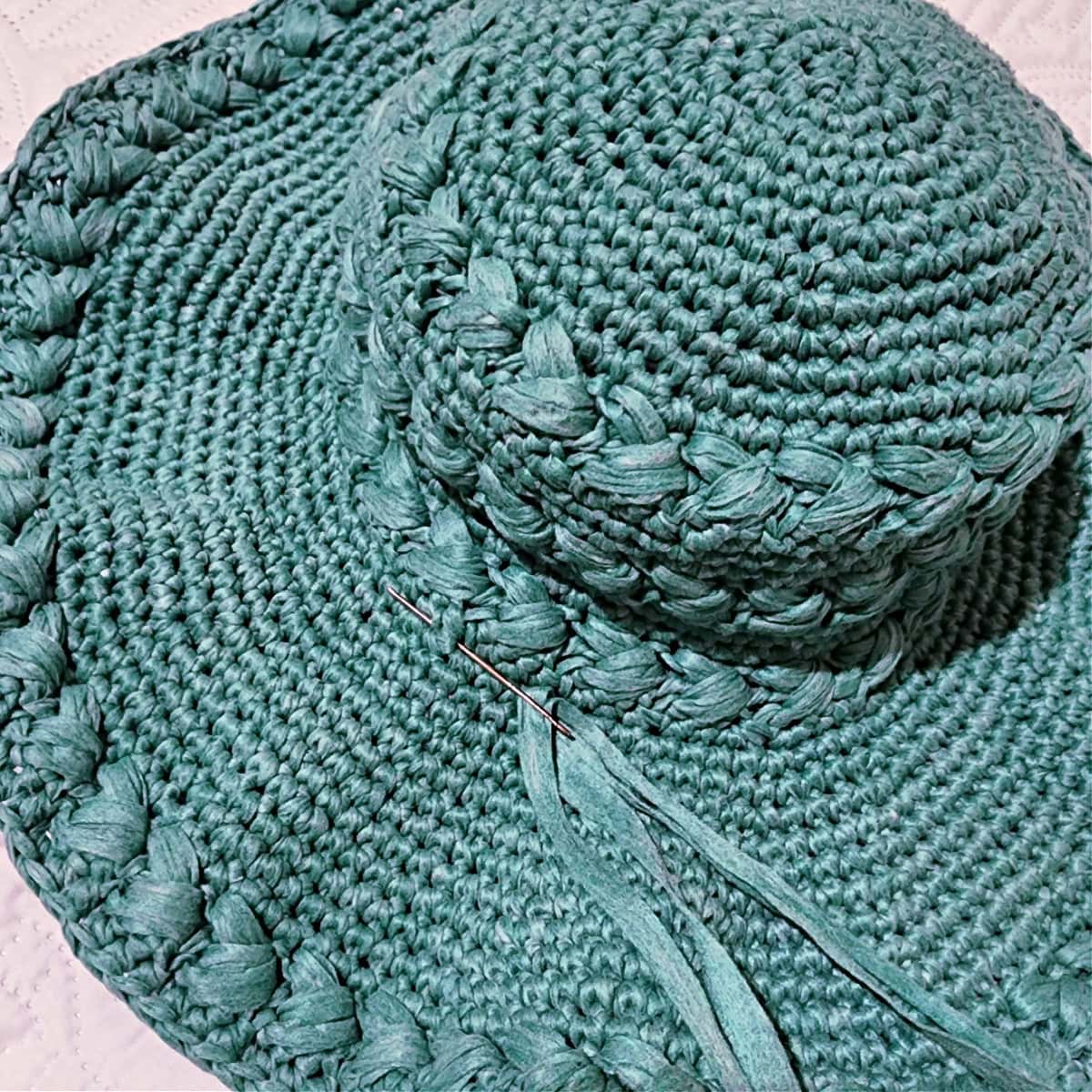 Close up of a crochet sun hat when attaching a band of yarn for a bow.