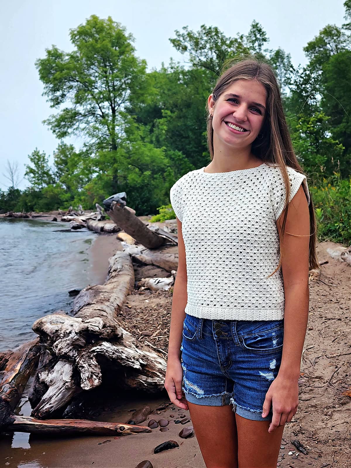 Cream colored crochet top for girls modeled by a beach.