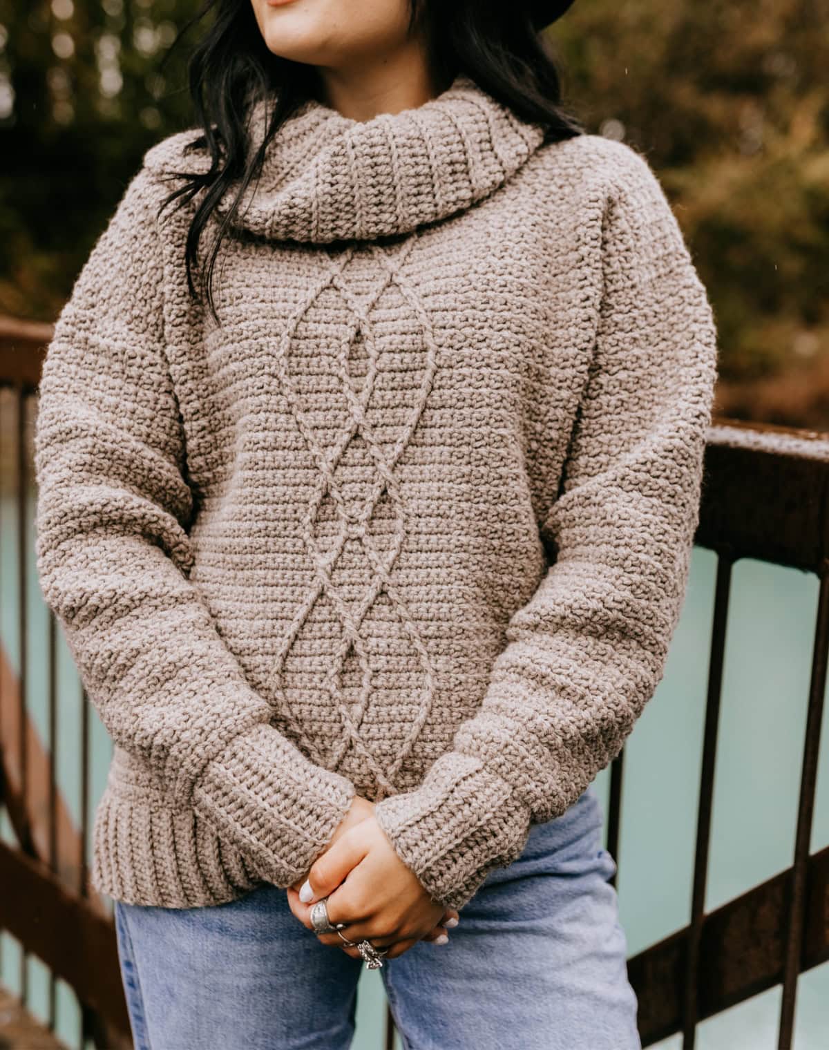 Close up of a cowl neck crochet sweater with cables.