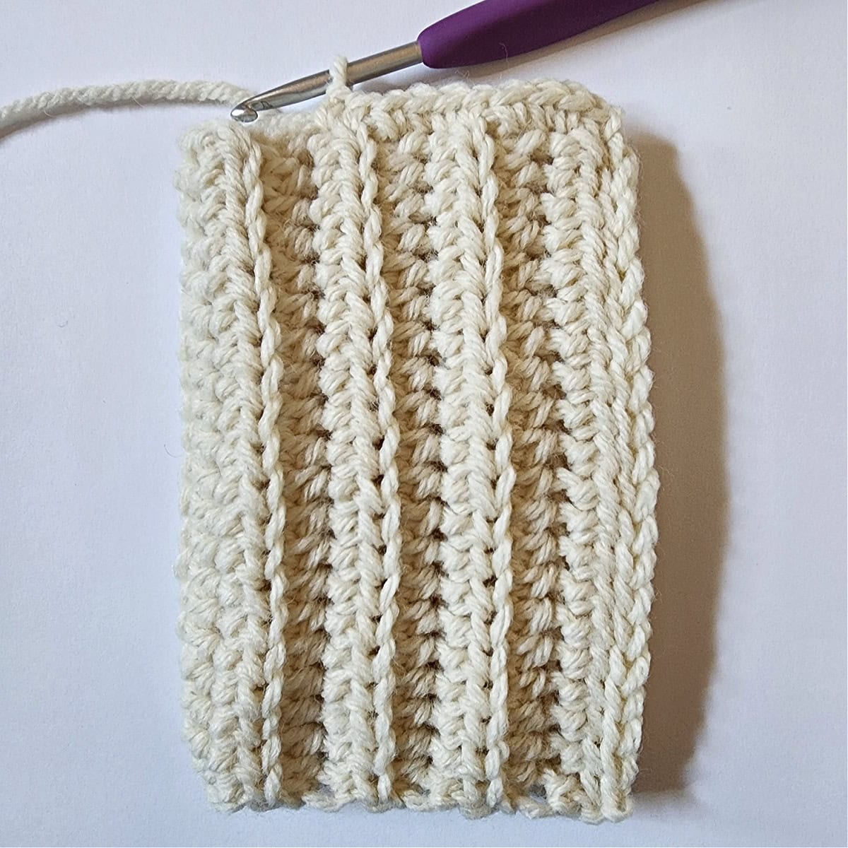 Crochet mitten being worked onto a ribbed crochet cuff.