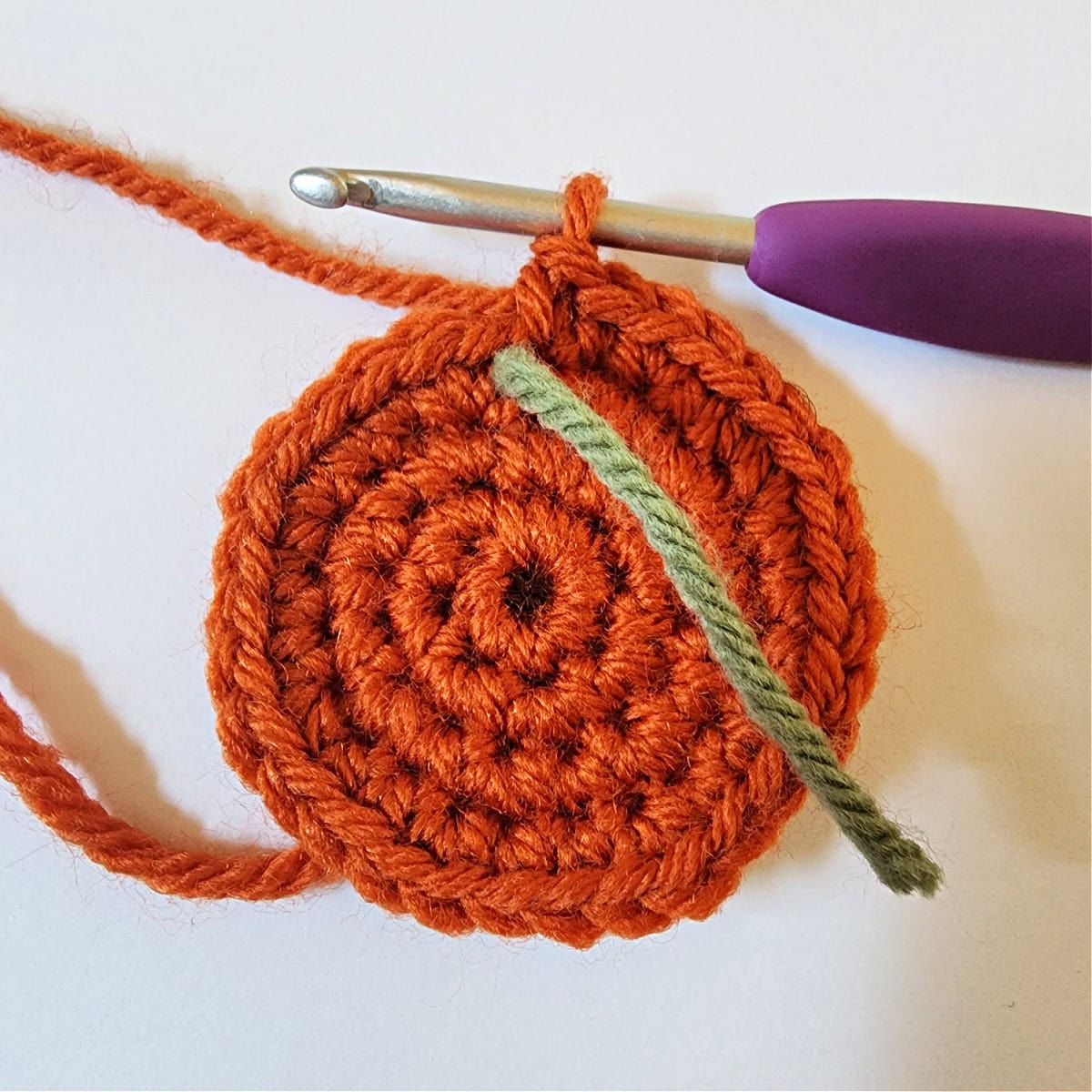 Small orange crochet circle for the base of a tiny crochet pumpkin.