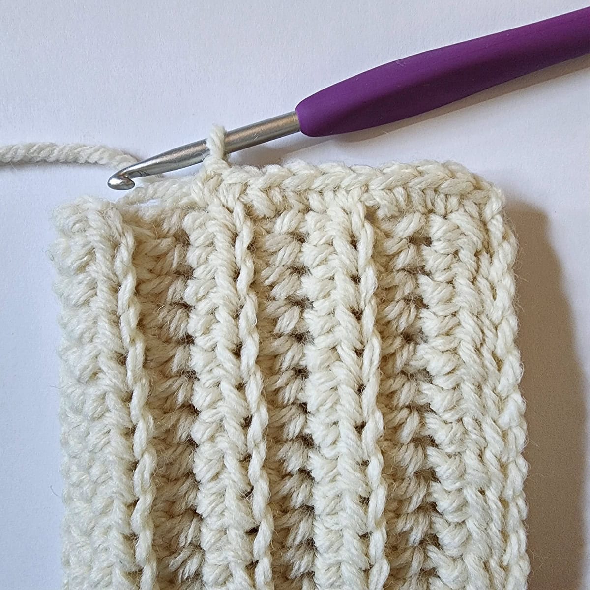 Close-up of a slouchy crochet beanie hat being crocheted onto a stretchy hat band.