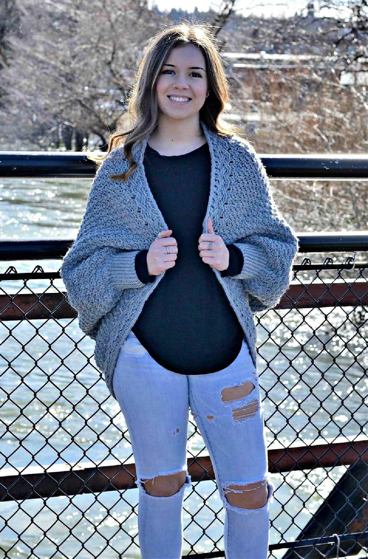 Young girl wearing a crochet cocoon cardigan and light ripped jeans.