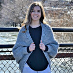 A girl standing on a bridge wearing a crochet cocoon cardigan.