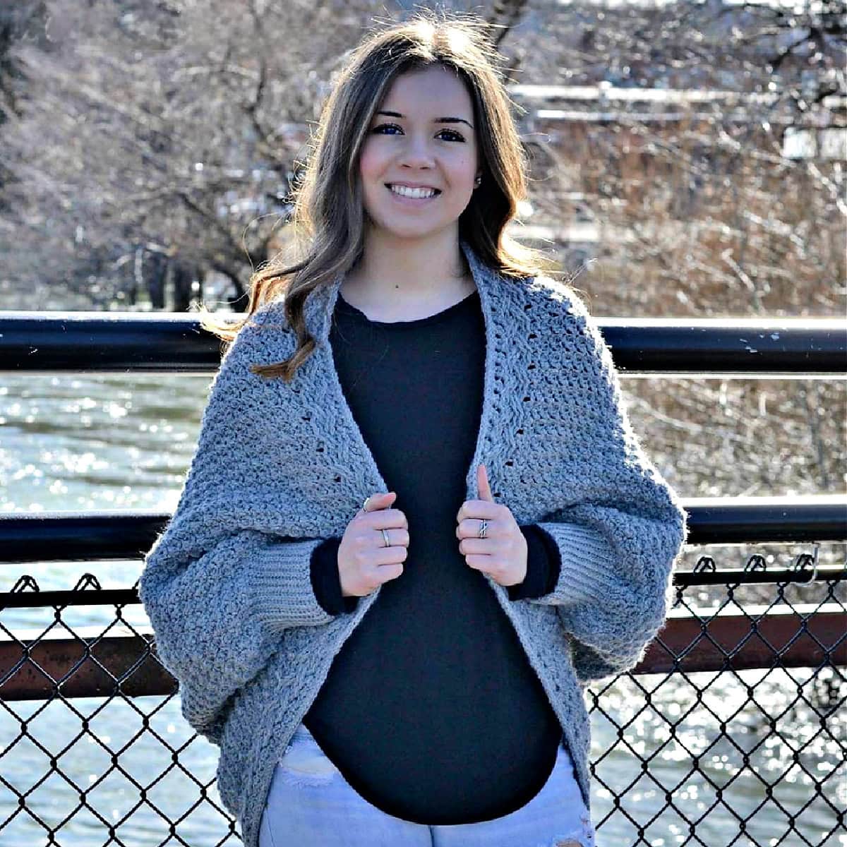 A girl standing on a bridge wearing a crochet cocoon cardigan.