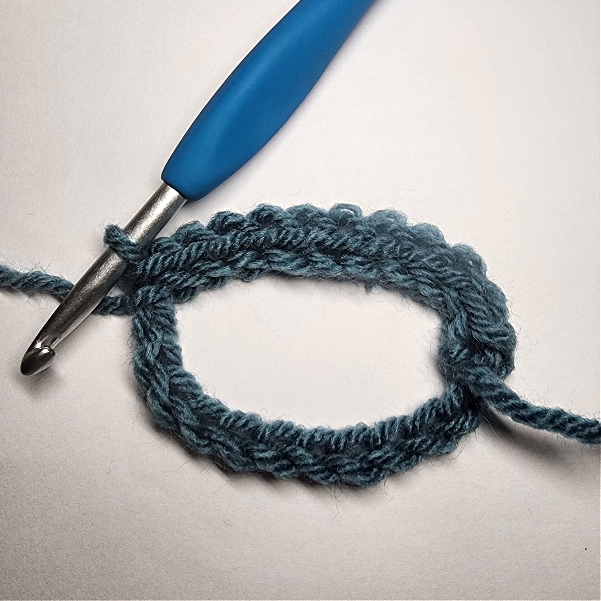 A crochet chain loop created to hold a mug cozy onto a coffee cup.