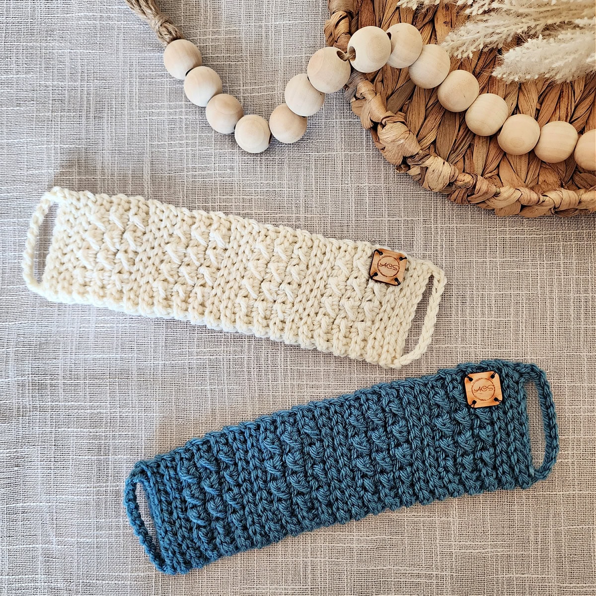 Two crochet mug cozies laying flat on a surface with wooden beads.