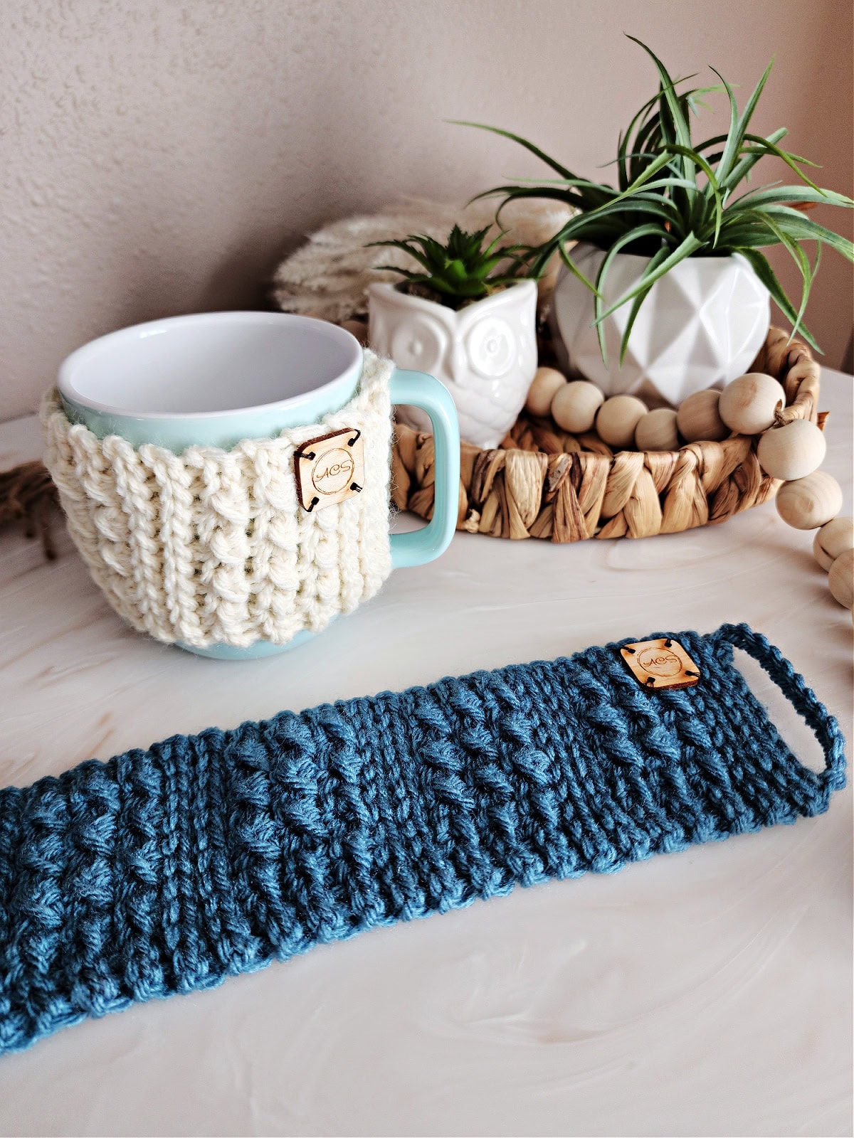 Blue coffee mug with a cream colored crochet coffee mug cozy.