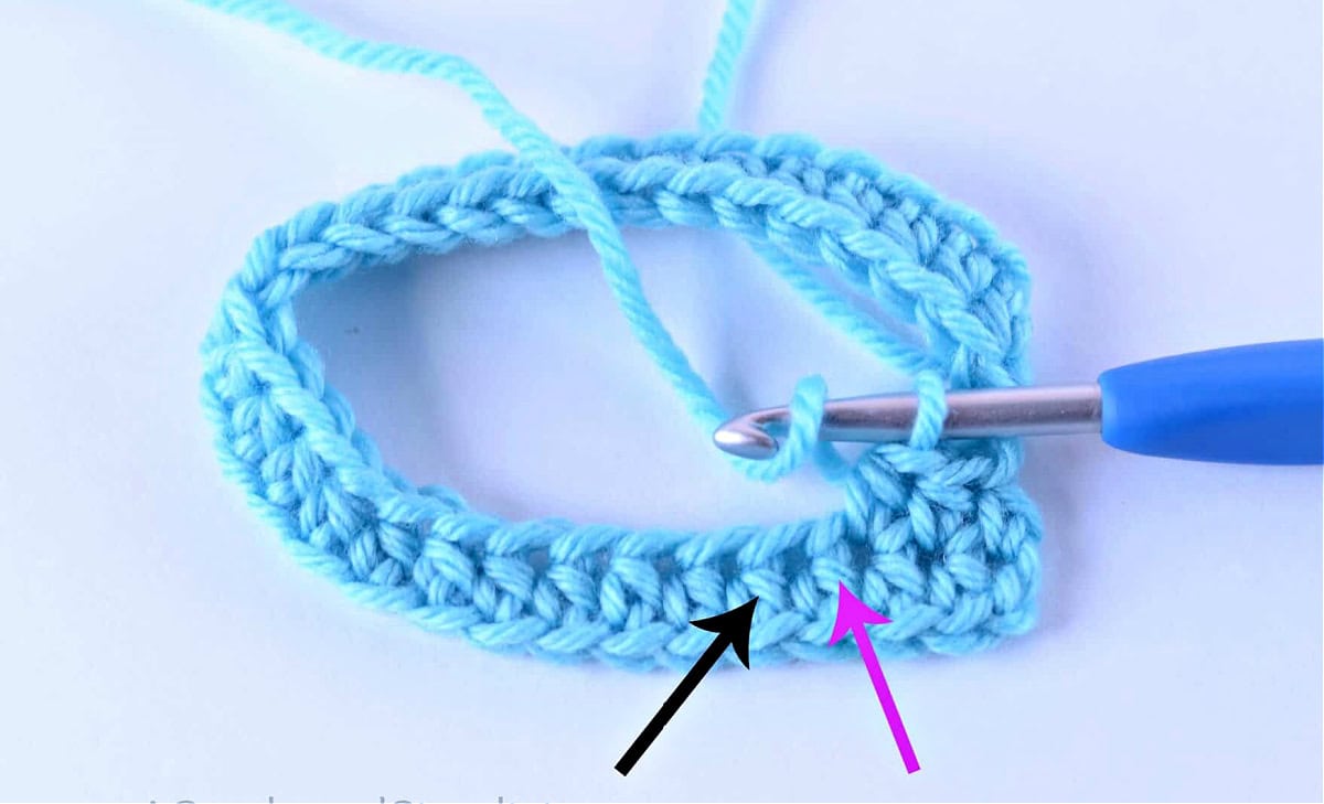 A swatch of stitches worked in the round and two arrows pointing to the posts of the next two stitches.