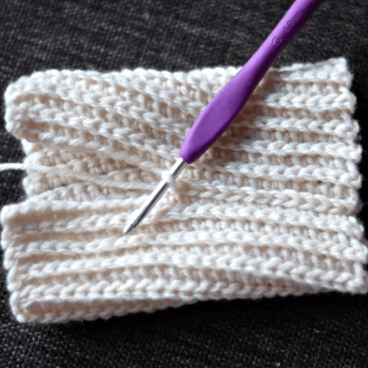 Purple crochet hook showing how to slip stitch seam a stretchy cuff.