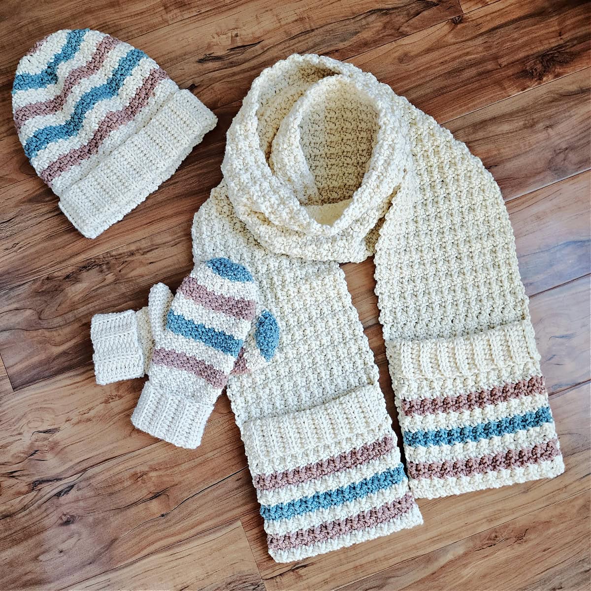 Cream and striped crochet beanie, mittens, and scarf coordinating set.