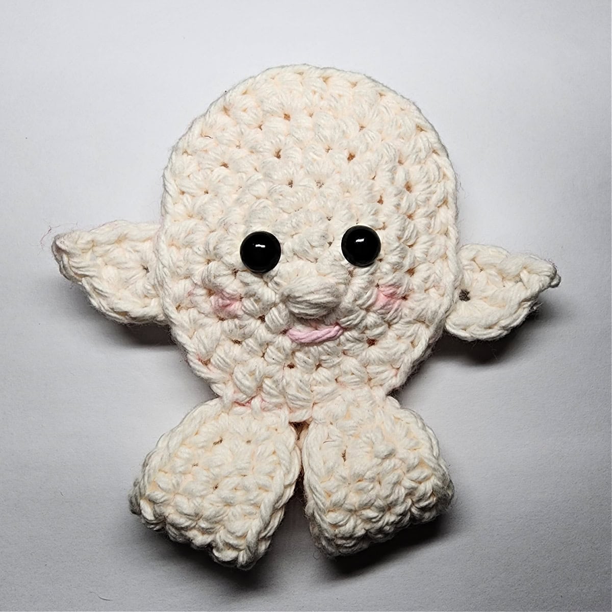 A crochet elf ornament with the face, ears, and hands attached, but no hat.