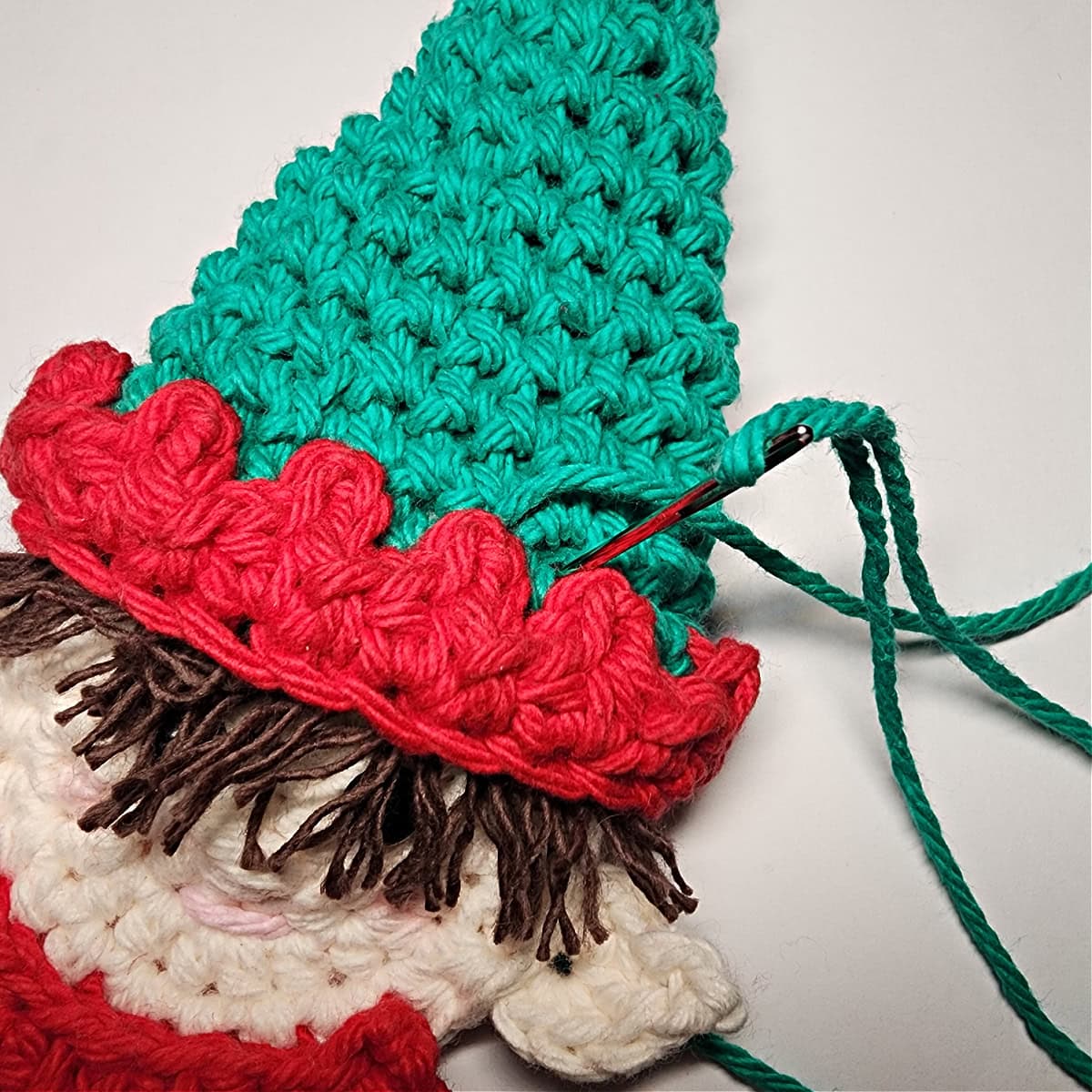 How to attach an elf hat to the top of the Christmas elf.