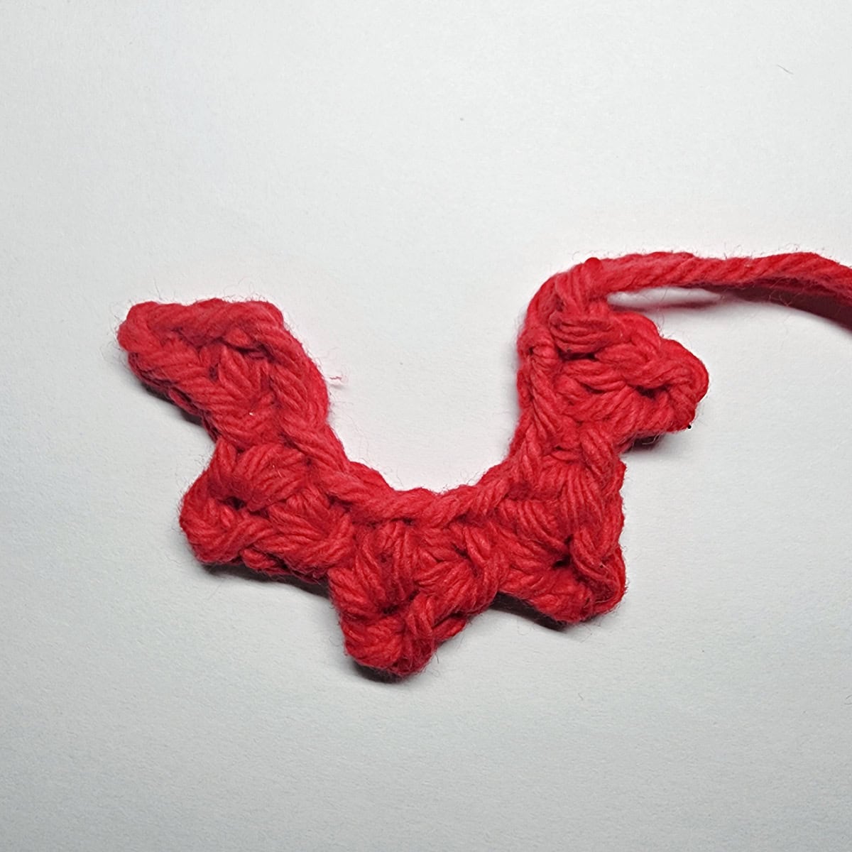 A red crochet elf collar laying on a white background.