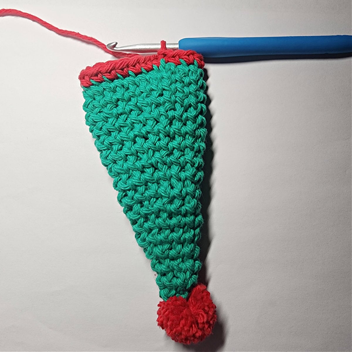 A green elf hat with small red yarn pom.