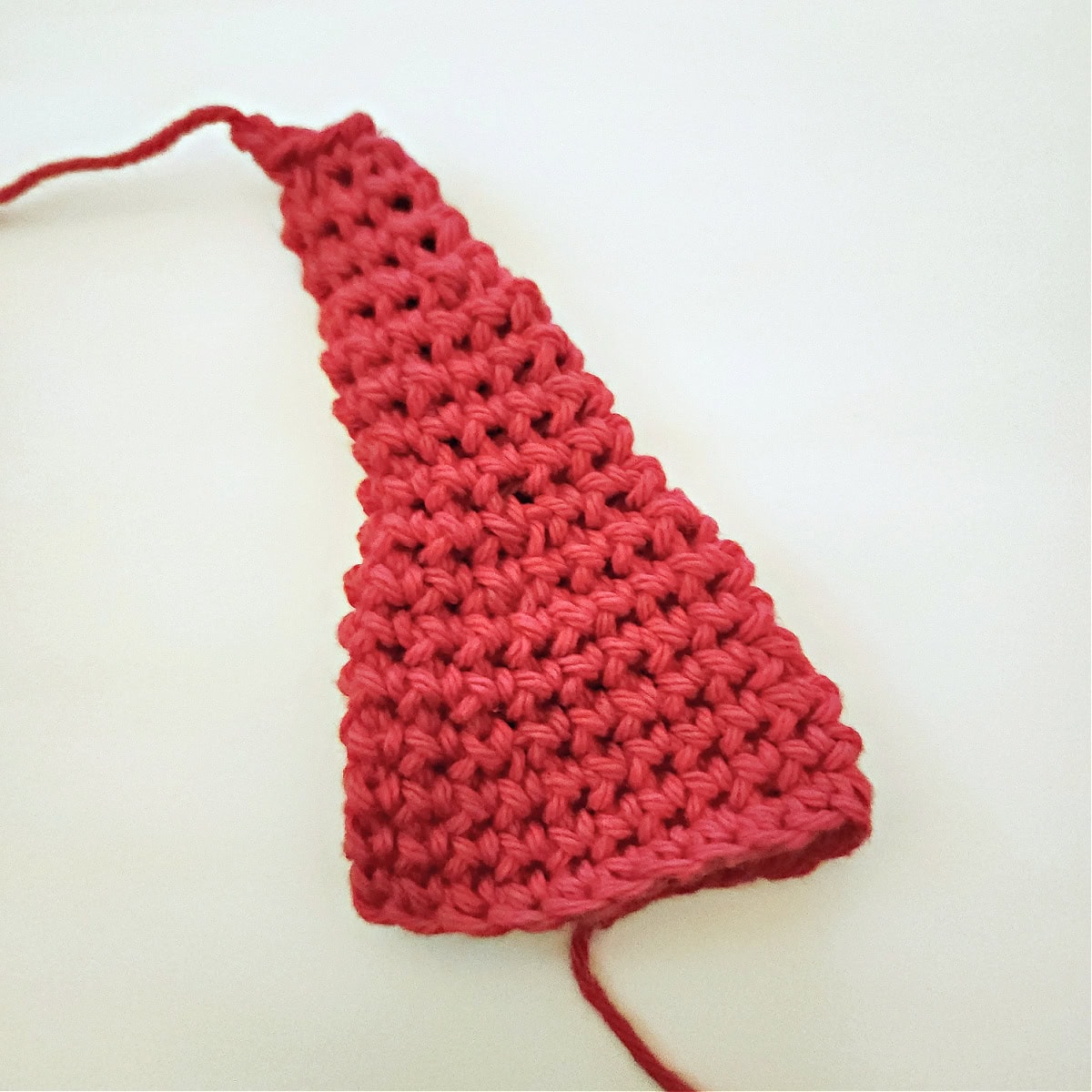 A red triangular crochet Santa elf hat.