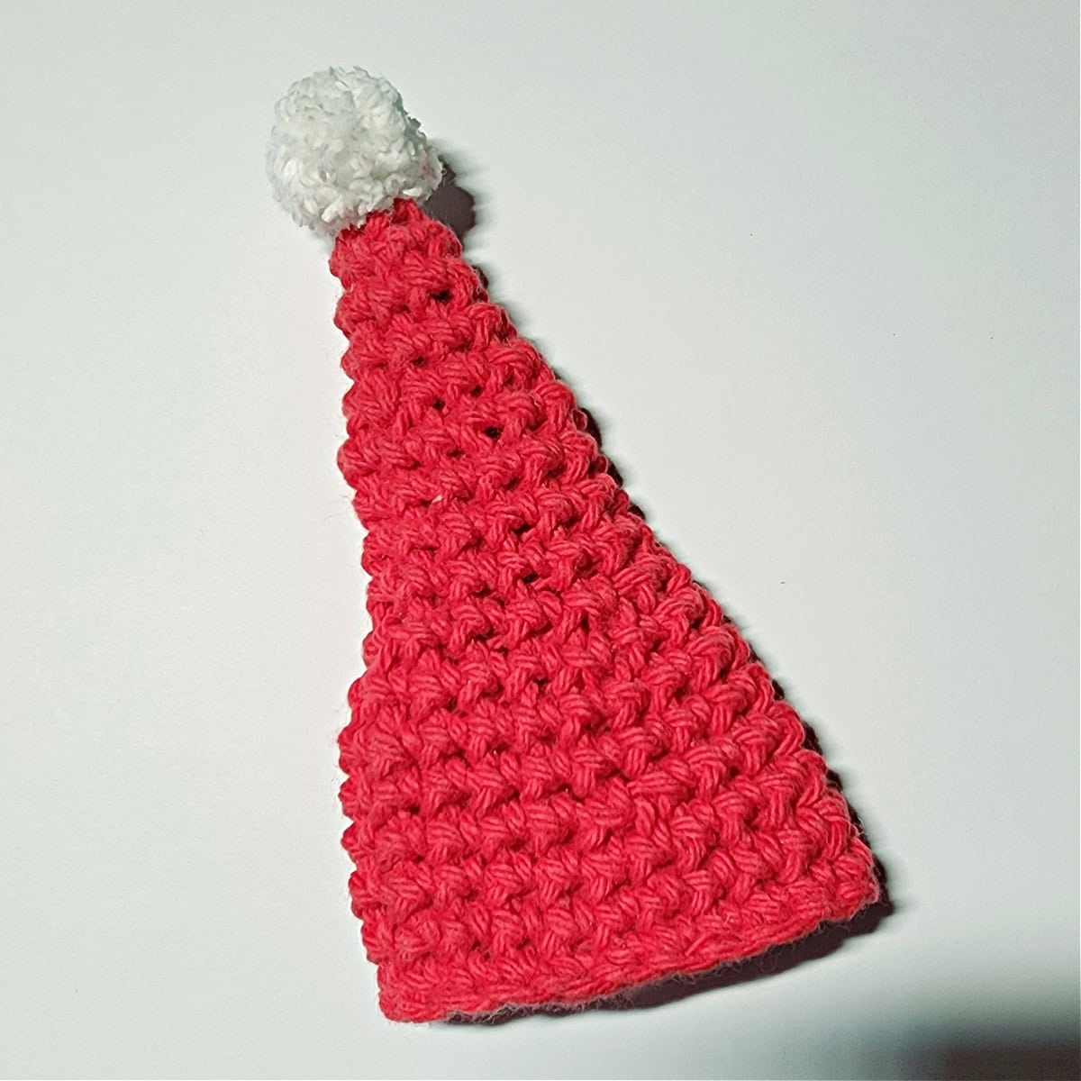 Mini crochet Santa hat with a white yarn pom attached.