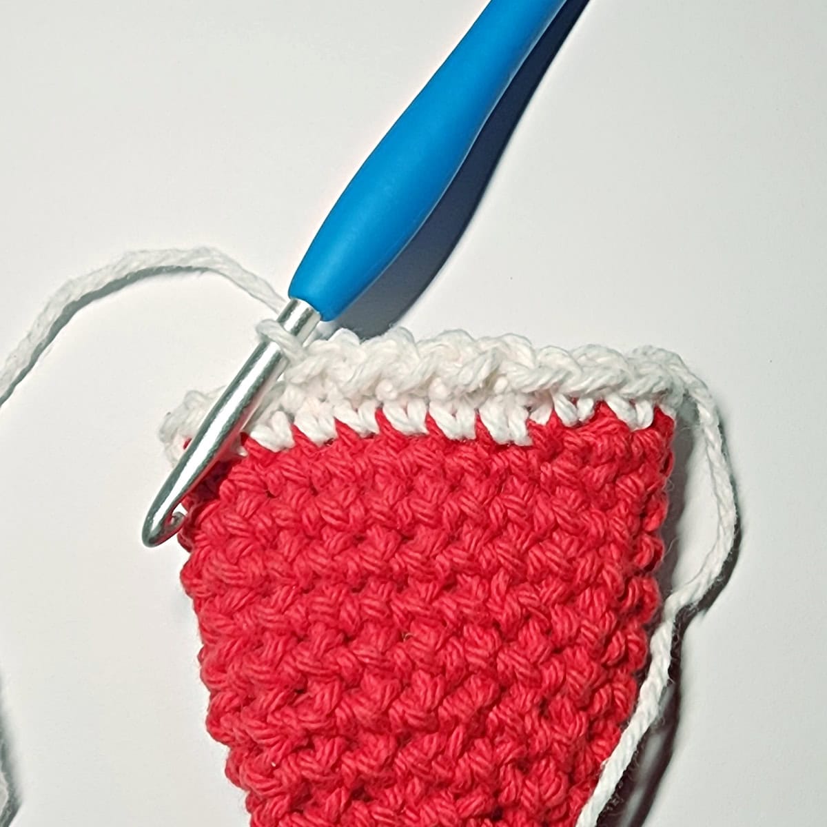 Crochet hook showing round two of the fur trim on Santa's hat.