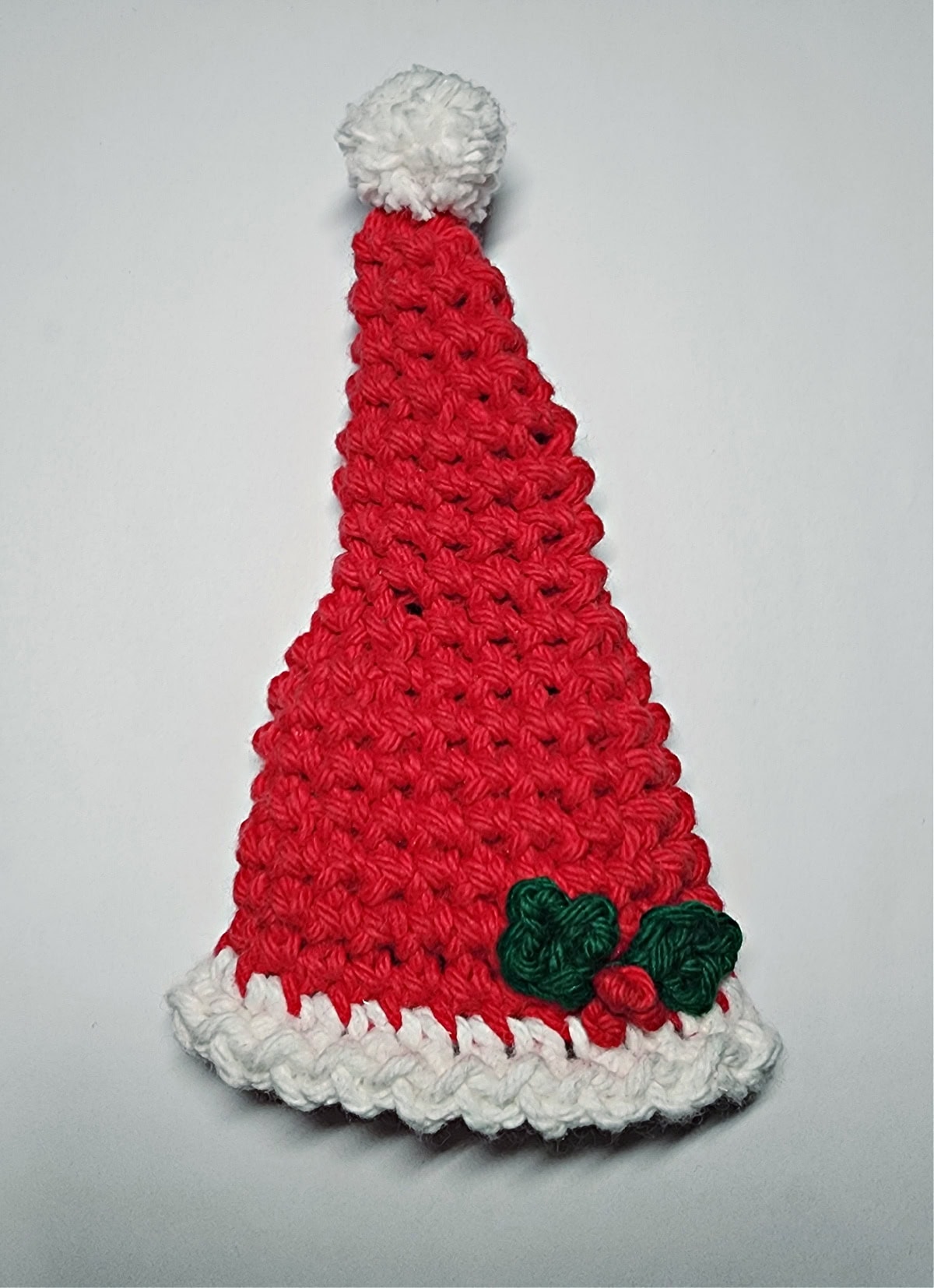 Crochet Santa hat with holly berries and leaves.