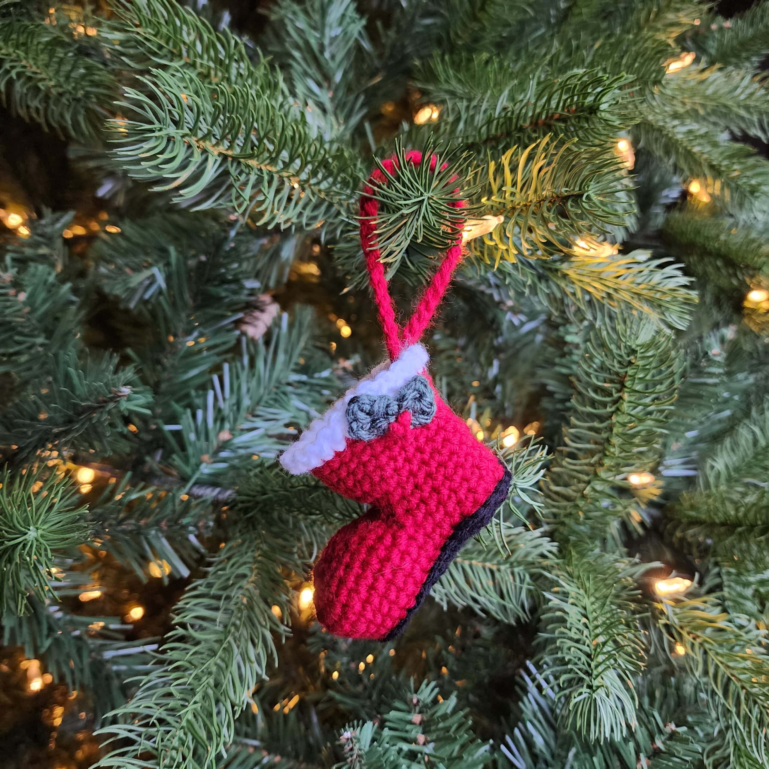 Red crochet Santa boot ornament with holly leaves and berries.