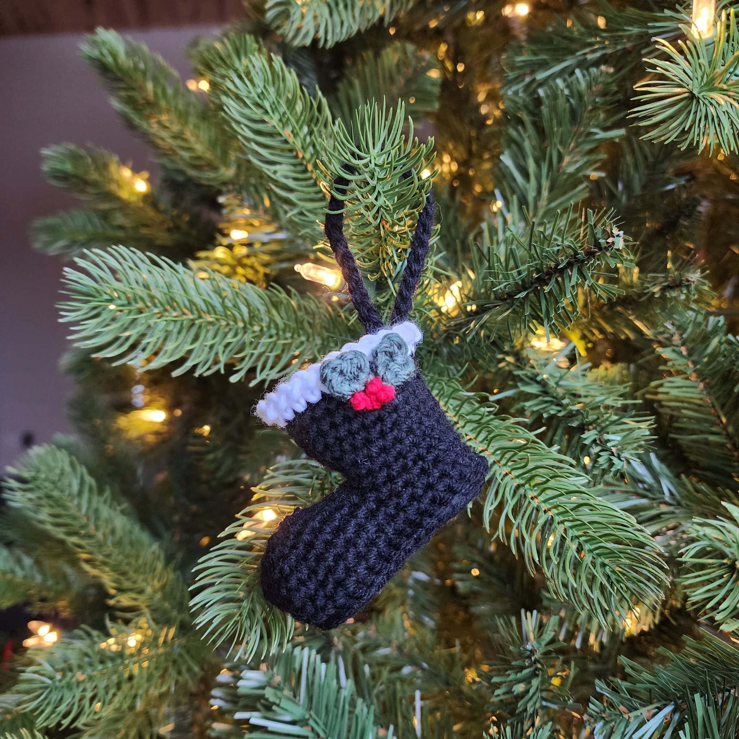 Black crochet Santa boot ornament with holly leaves and berries.