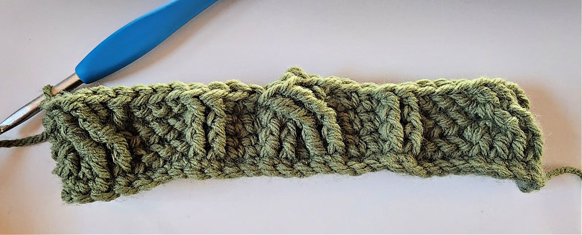 Green crochet Christmas stocking with a celtic crochet cable stitch pattern round 4.