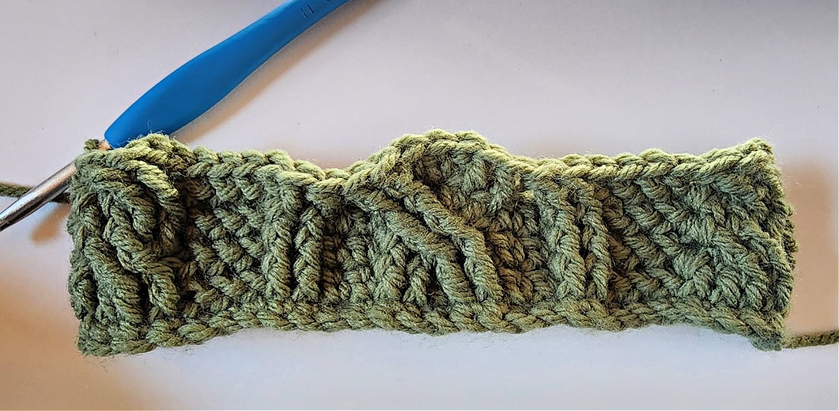 Green crochet Christmas stocking with a celtic crochet cable stitch pattern round 5.