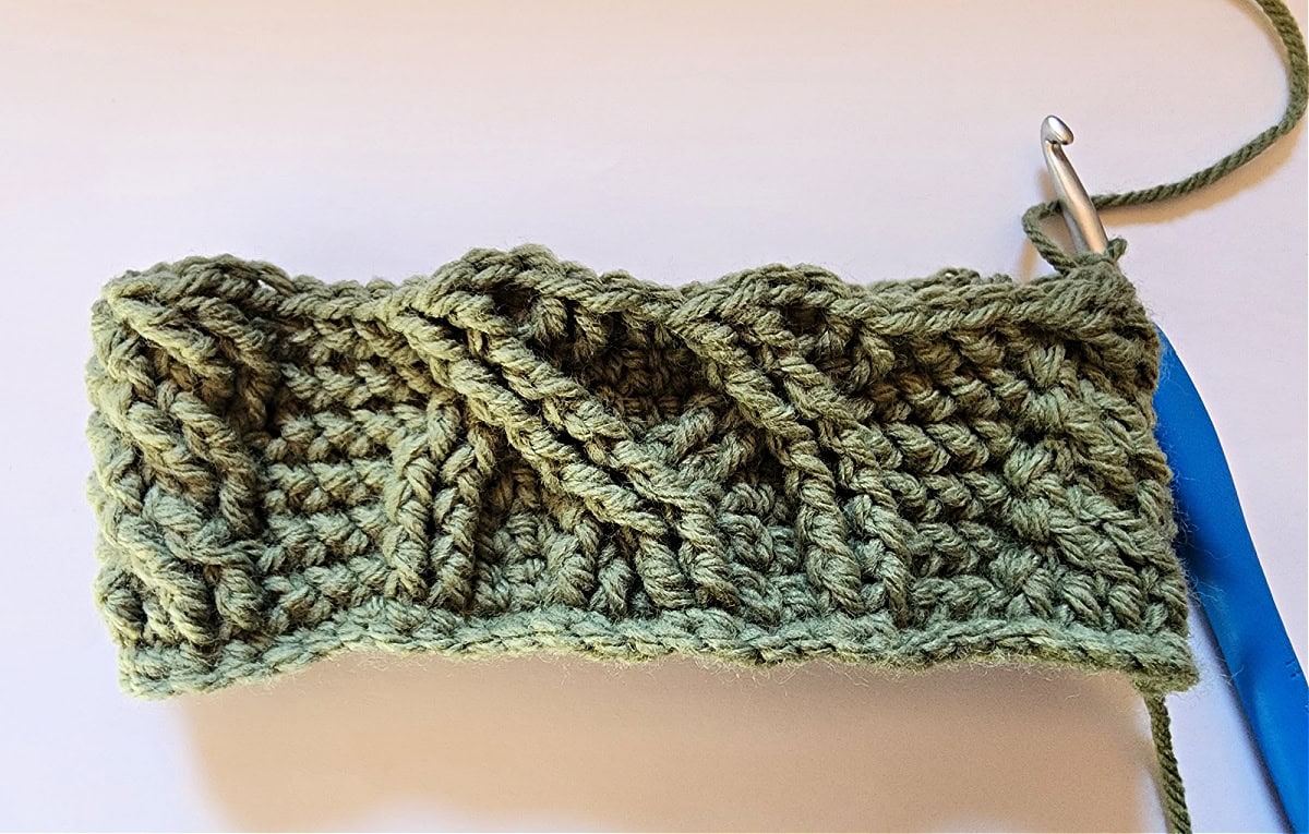 Green crochet Christmas stocking with a celtic crochet cable stitch pattern round 7.