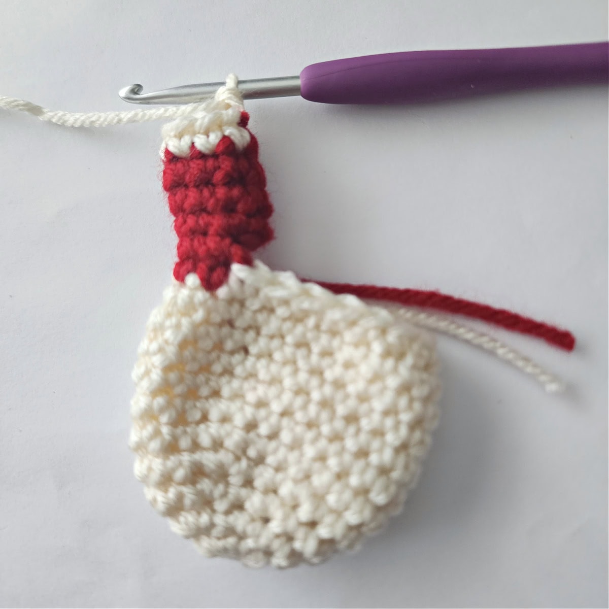 Changing colors of yarn to add a hand to the crochet amigurumi ornament.