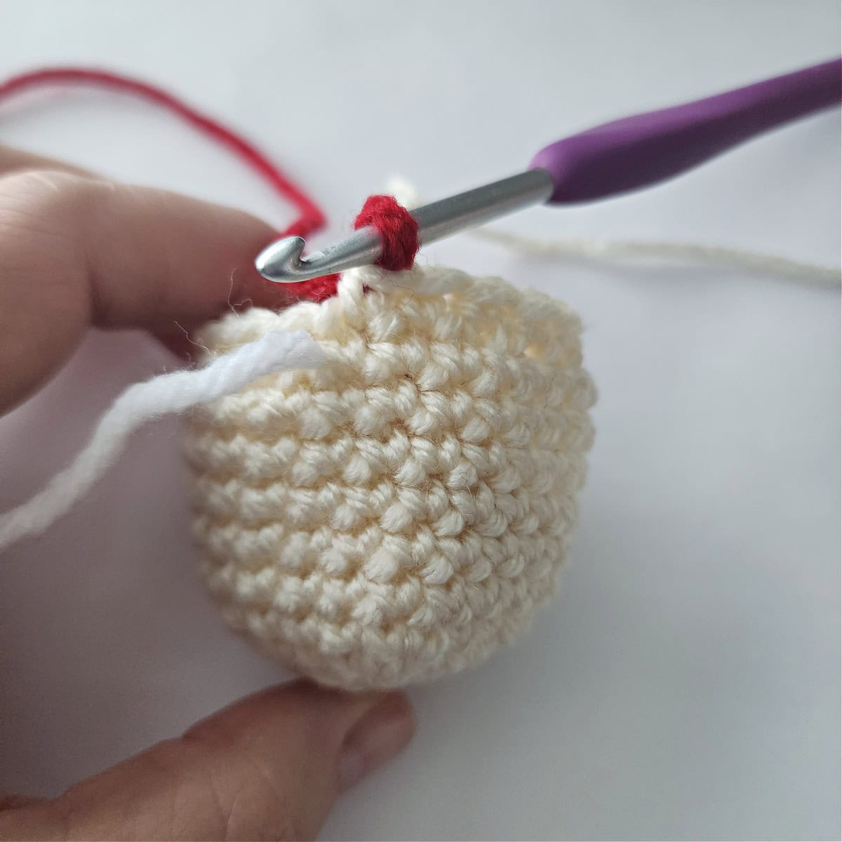 The head of an amigurumi crochet jingle bell ornament.