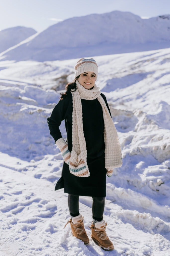 Crochet beanie, scarf, and mittens set worn by a woman in the Alaska snow.