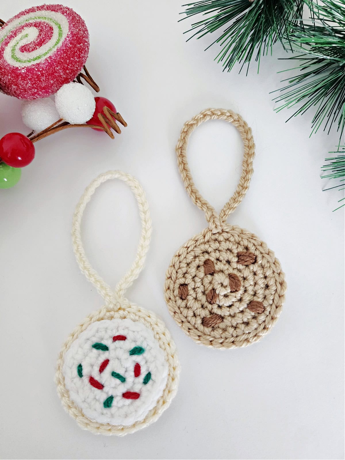 A crochet chocolate chip cookie and crochet sugar cookie laying on a white background.