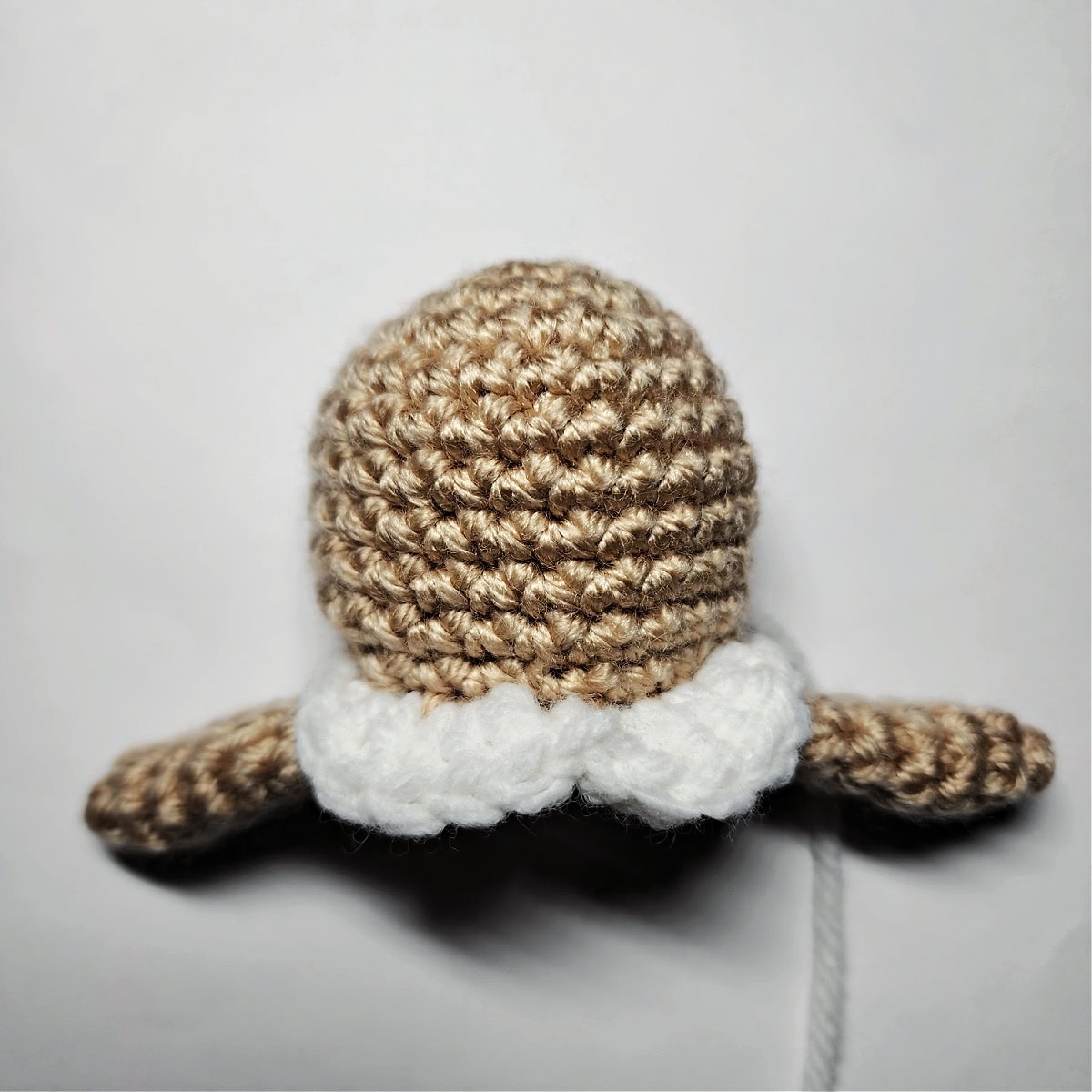 Plain brown crochet gingerbread body for an ornament with a white collar.