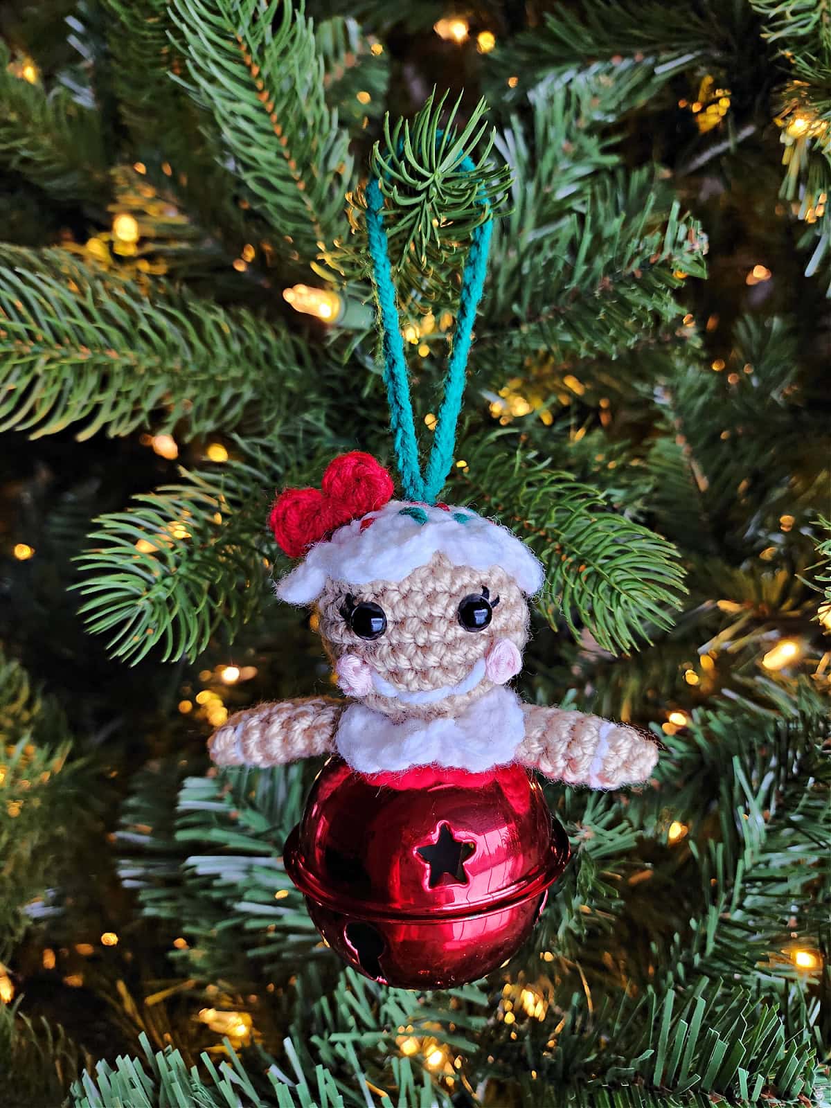 Crochet gingerbread girl ornament hanging on a Christmas tree.