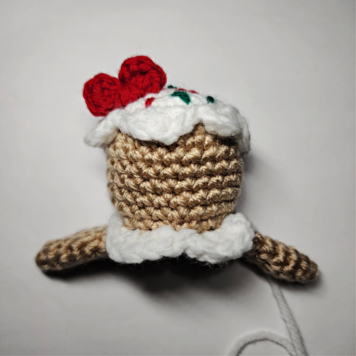 Mini red crochet bow sewn onto the top of the gingerbread girl's head.