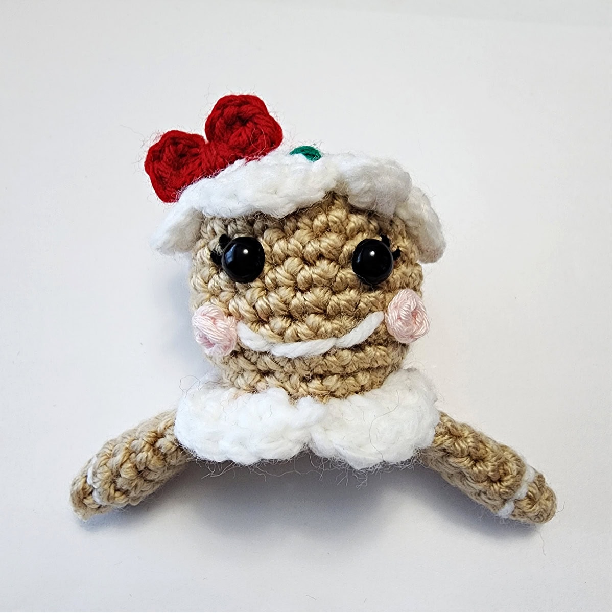 The crocheted ornament topper for a gingerbread girl is complete and ready to be attached to the jingle bell.