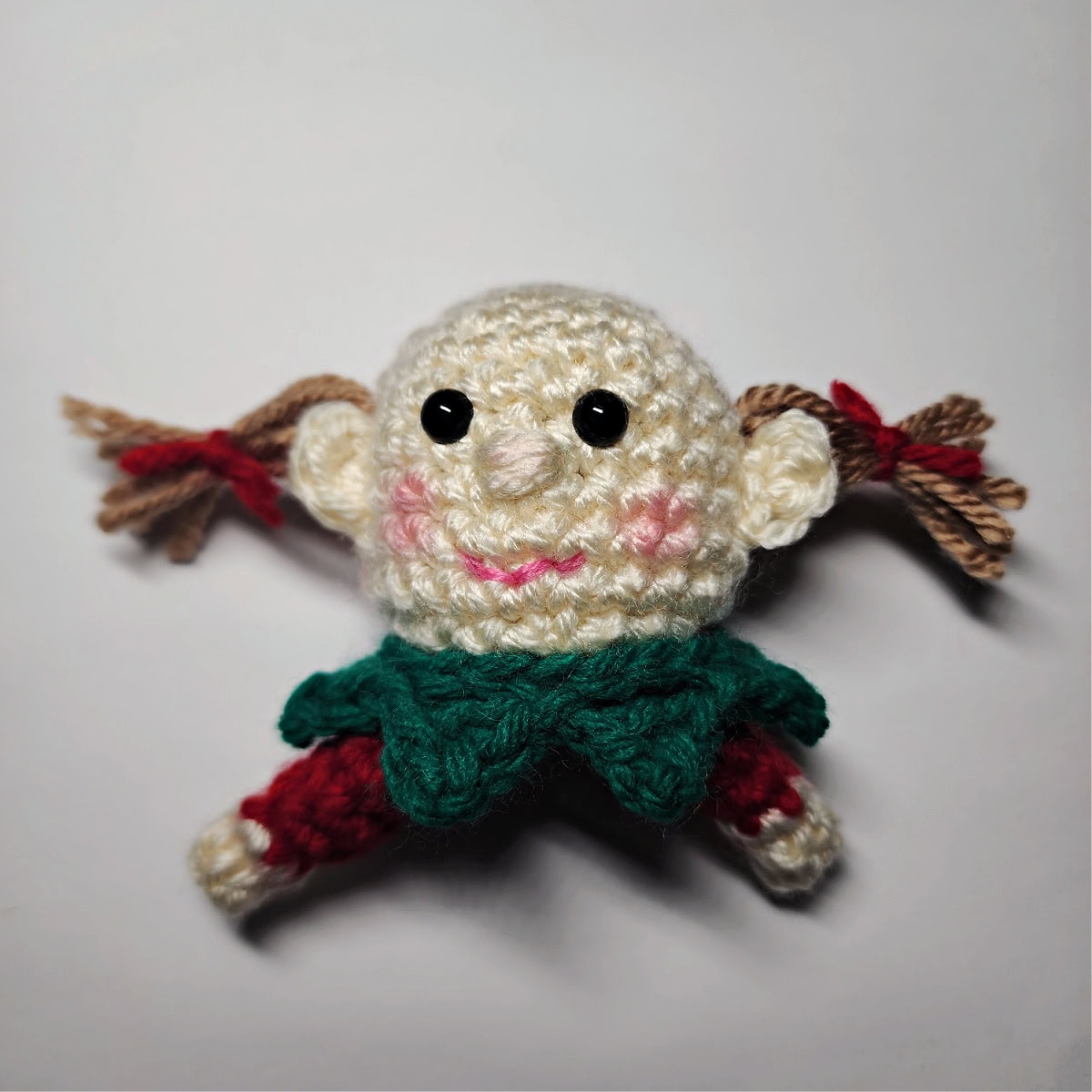 A photo showing where to attach the ponytails on a crochet girl elf ornament.