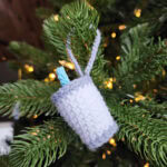 Milk for Santa crochet Christmas ornament hanging on a Christmas tree with a blue straw.