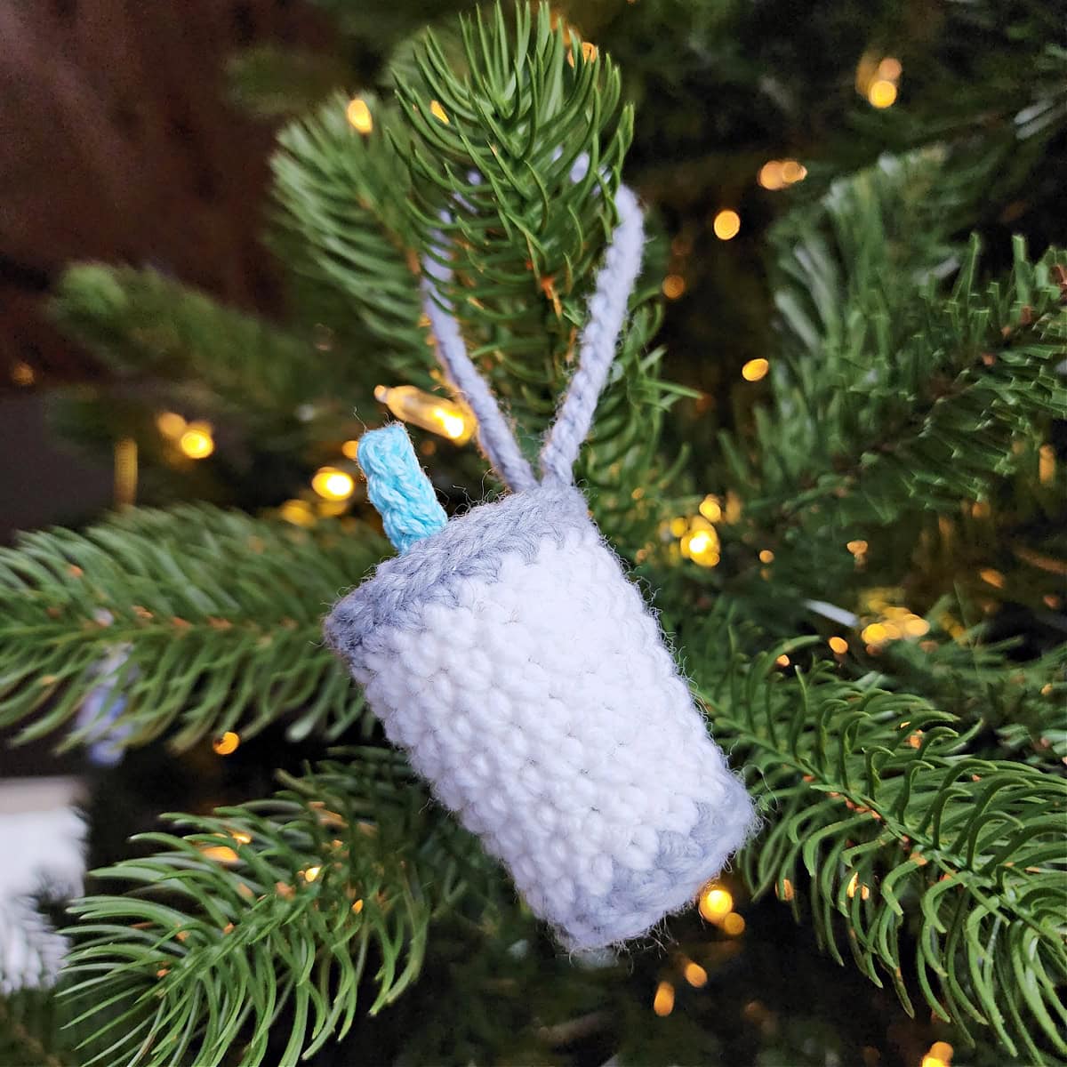 Milk for Santa crochet Christmas ornament hanging on a Christmas tree with a blue straw.