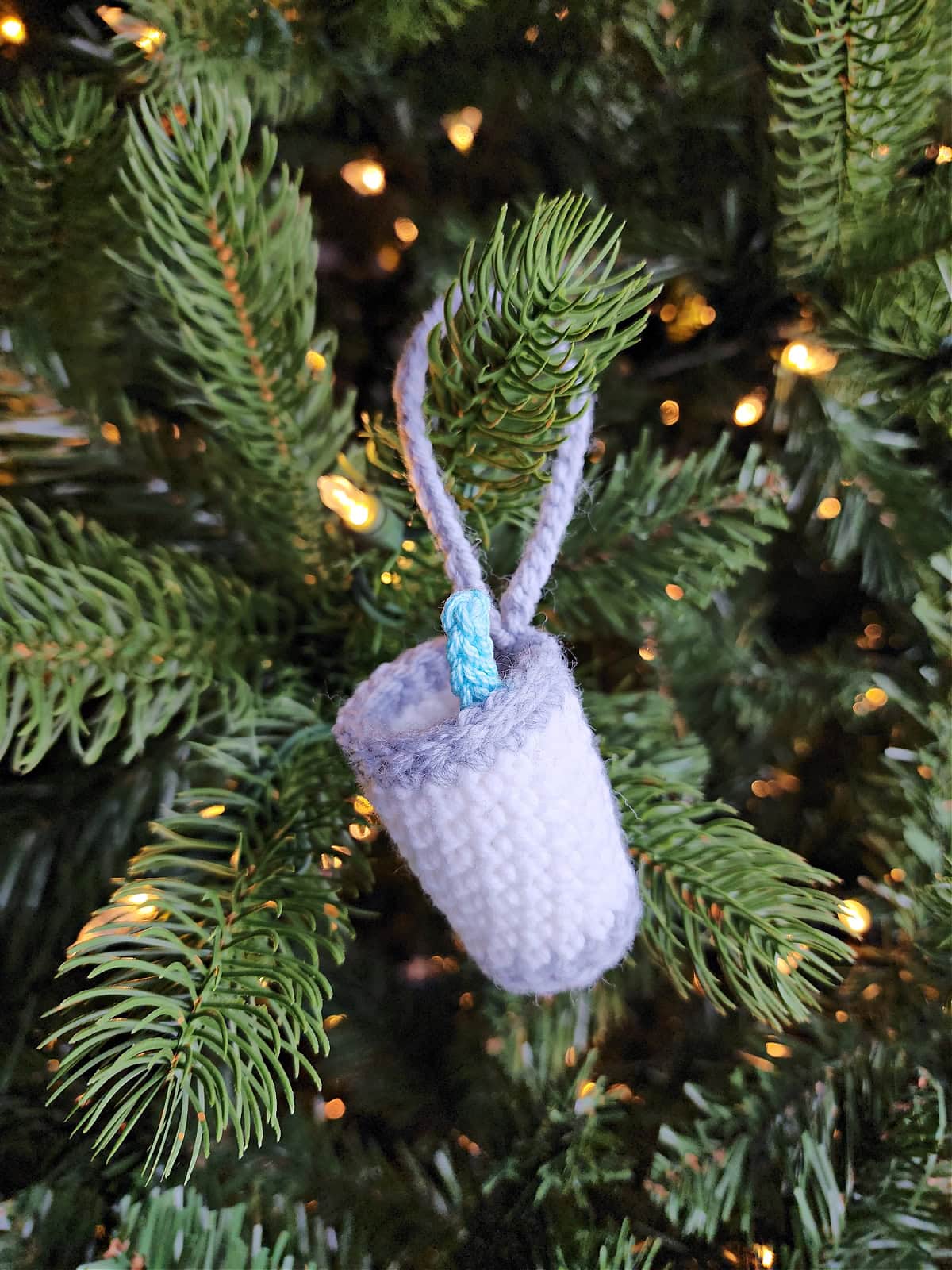 Milk for Santa crochet Christmas ornament with a tiny straw hanging on a pre-lit Christmas tree.