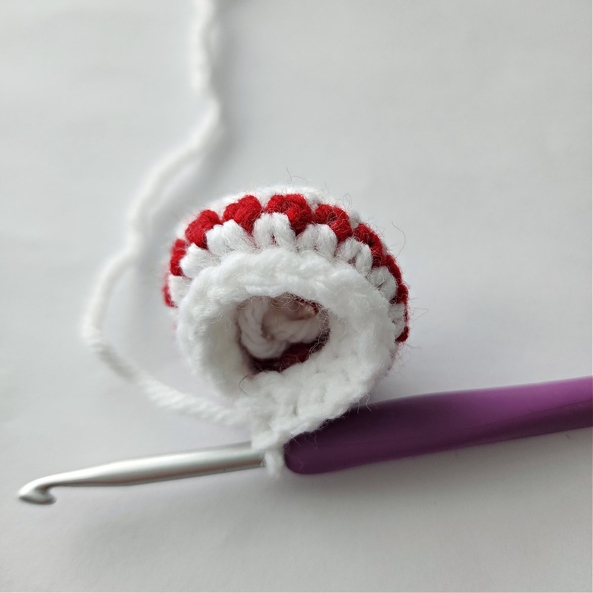 A crochet hook increasing around the bottom of the bun to make the crochet hair.