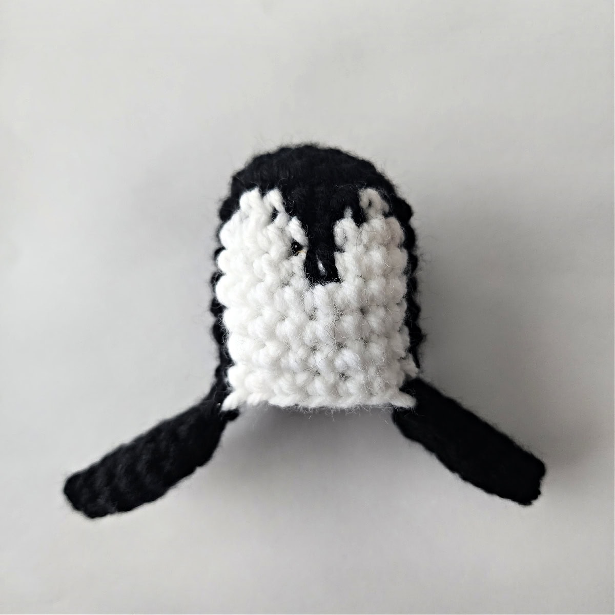 A mini crochet penguin head and wings.