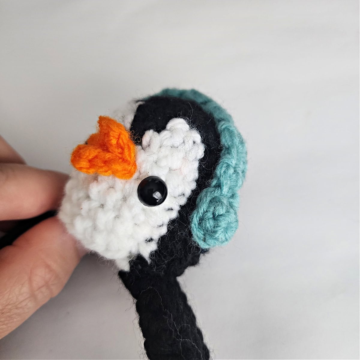 Close-up of a crochet penguin to show where to attach earmuffs, a beak, and eyes.