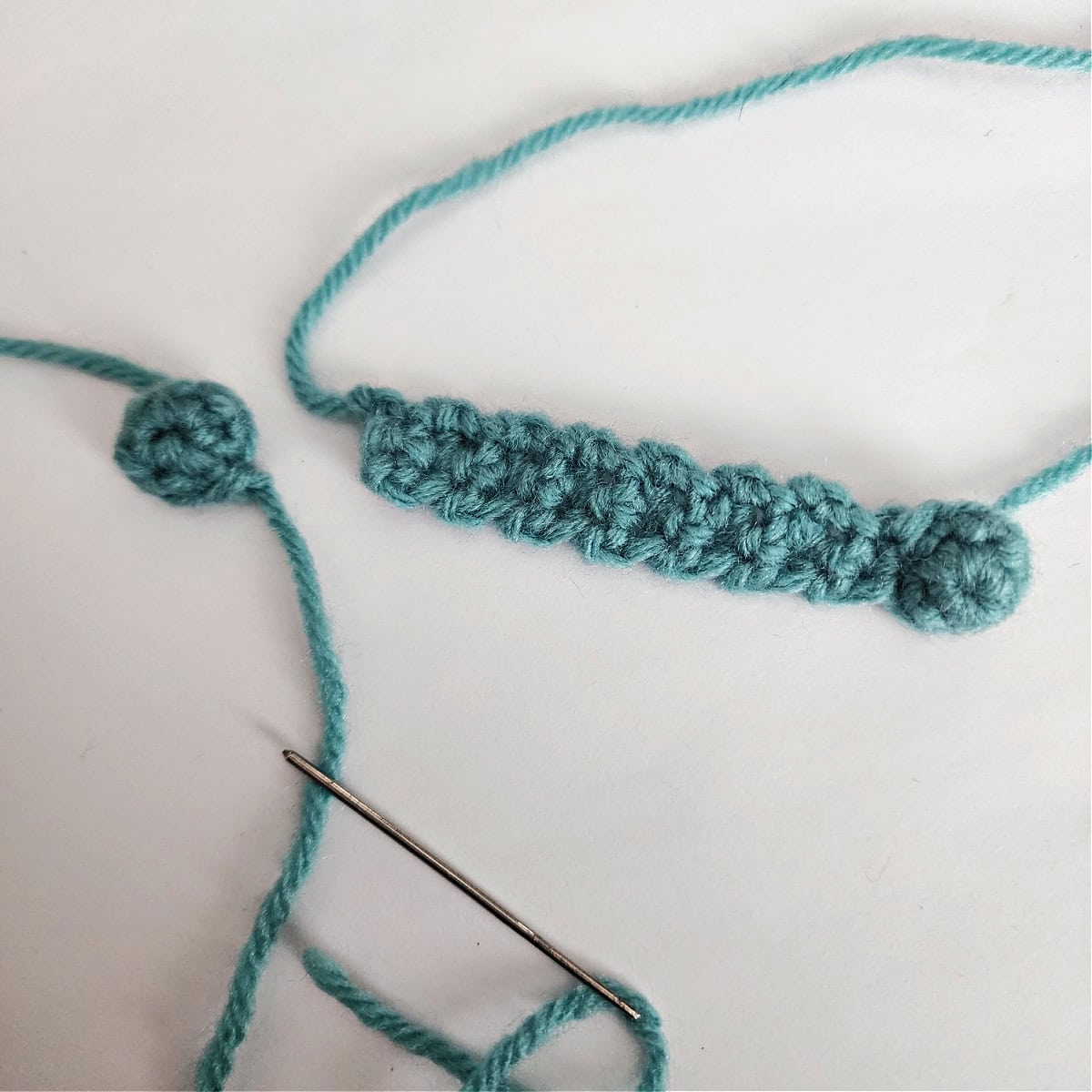 A photo showing how to join the second earmuff for a crochet penguin.