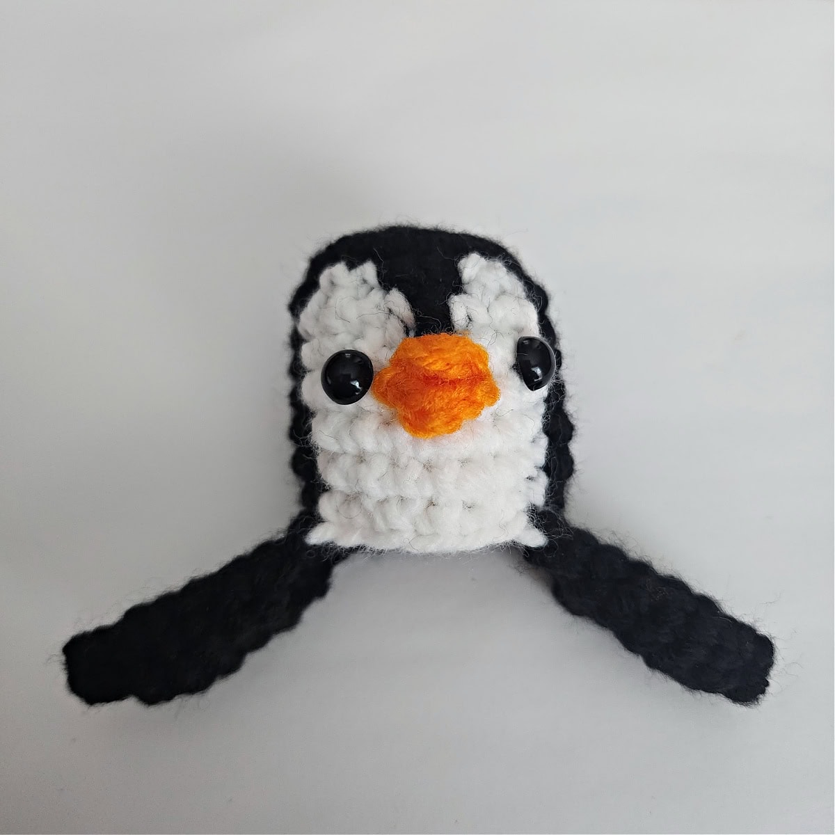 A photo showing where to position the safety eyes and beak on a crochet penguin.