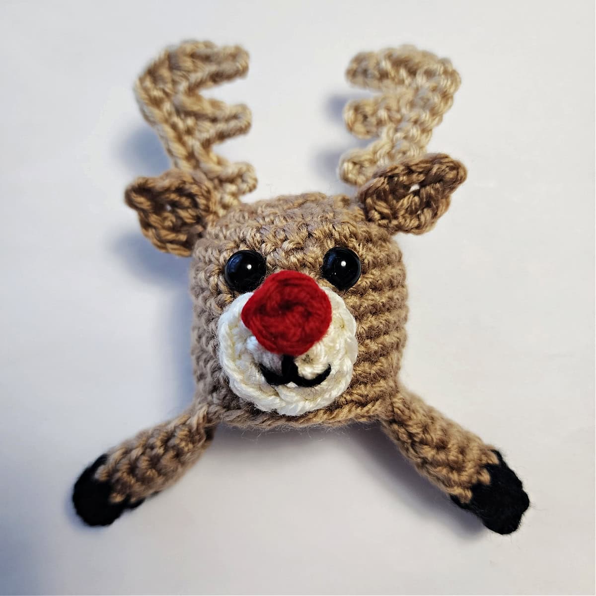 Crochet reindeer ornament all assembled and ready to be attached to a jingle bell.